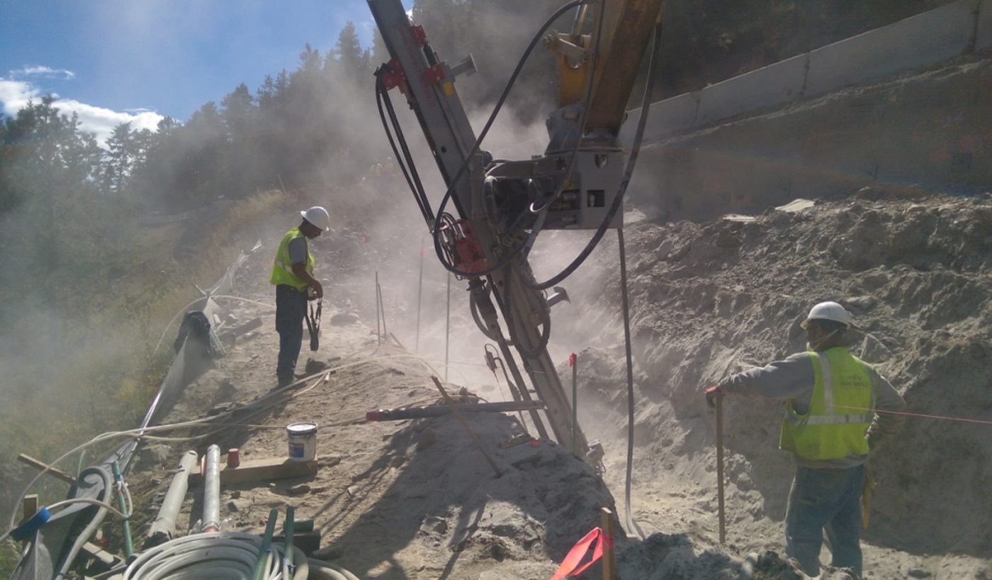 Park Range crew drilling micropiles with an excavator-mounted drill on the slope at the Crawford Gulch MSE wall