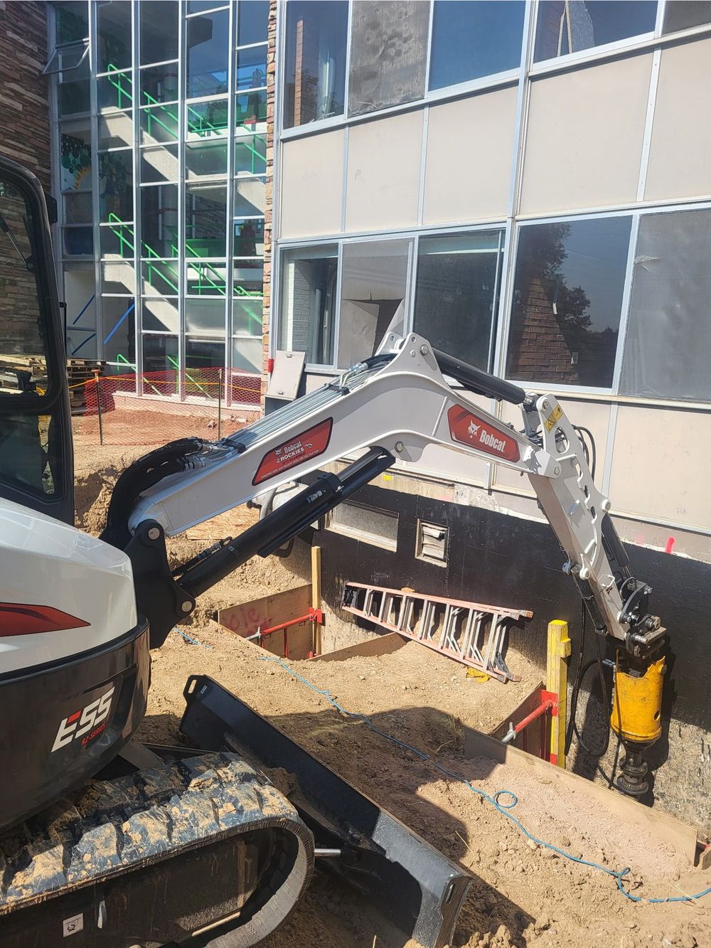 Park Range excavator installing helical piles beside Allison Hall at Colorado State University