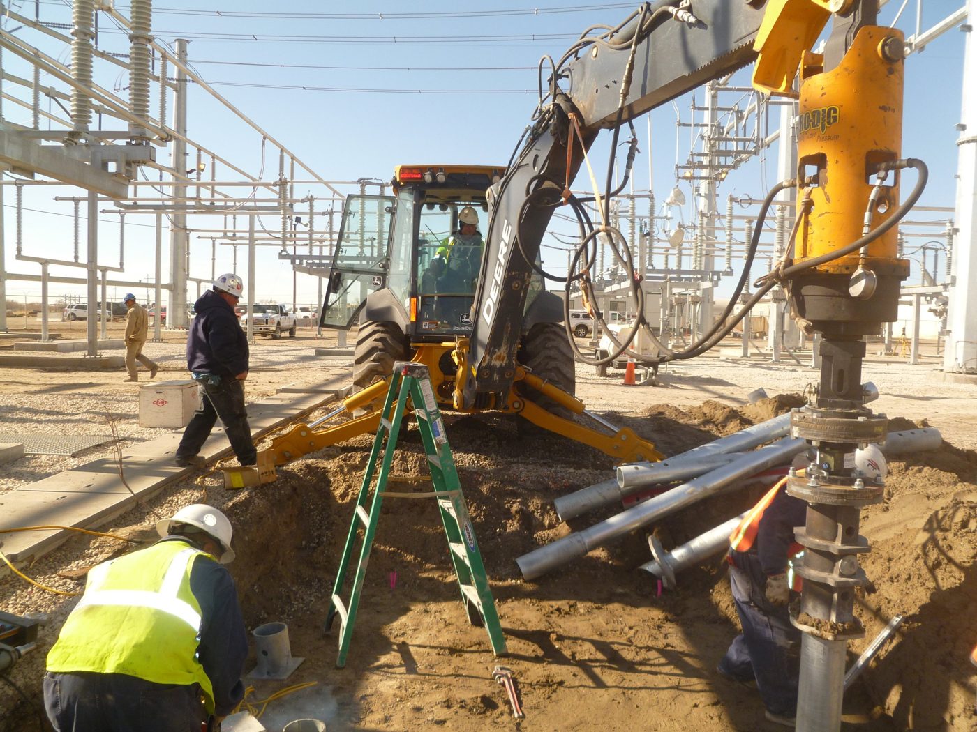 Park Range crew installing helical piles with a backhoe-mounted drive head inside the Dave Johnson Power Plant substation